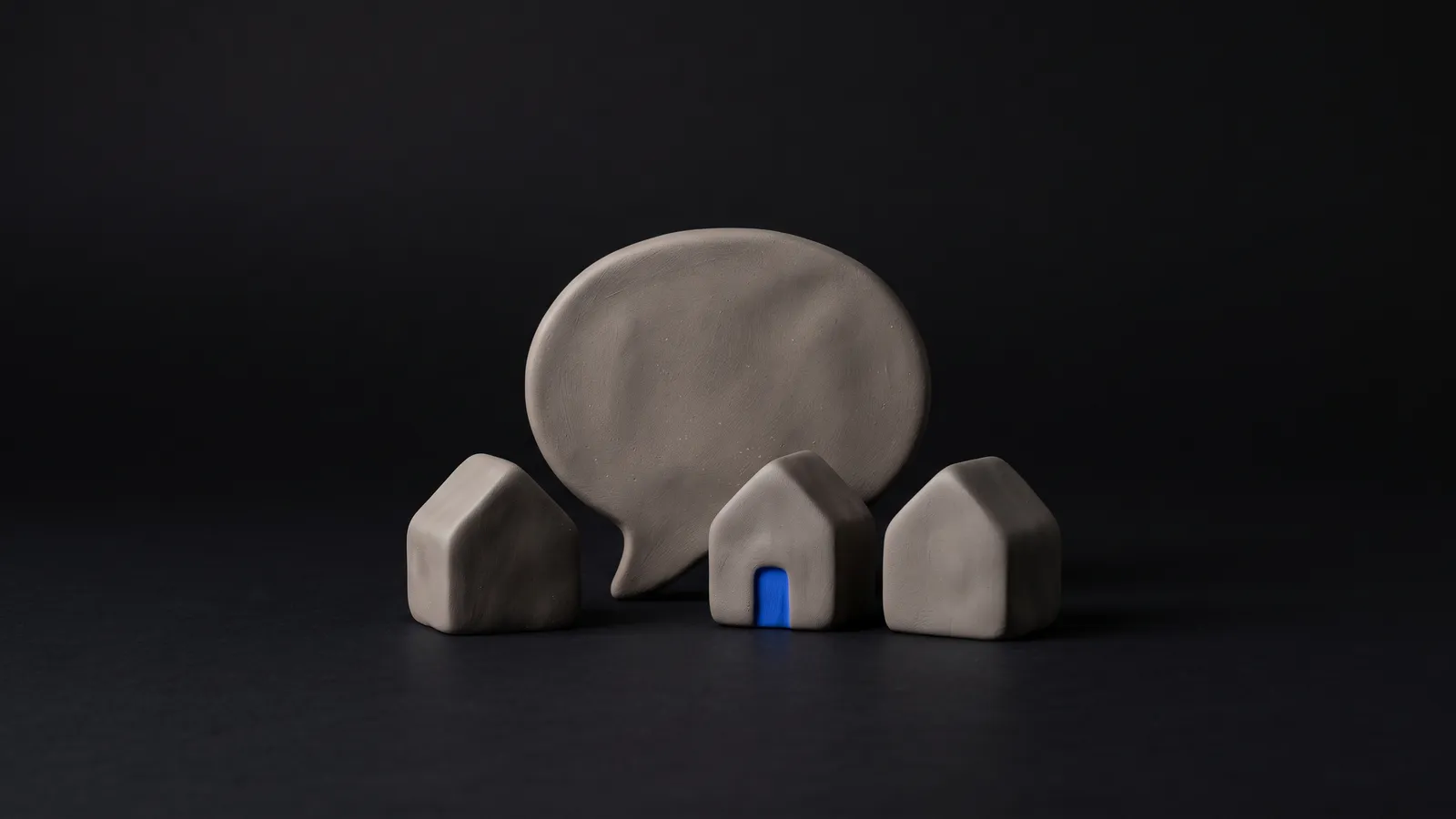 A matte clay magnifying glass resting over a small clay map pin with a cobalt tip, on a near-black background
